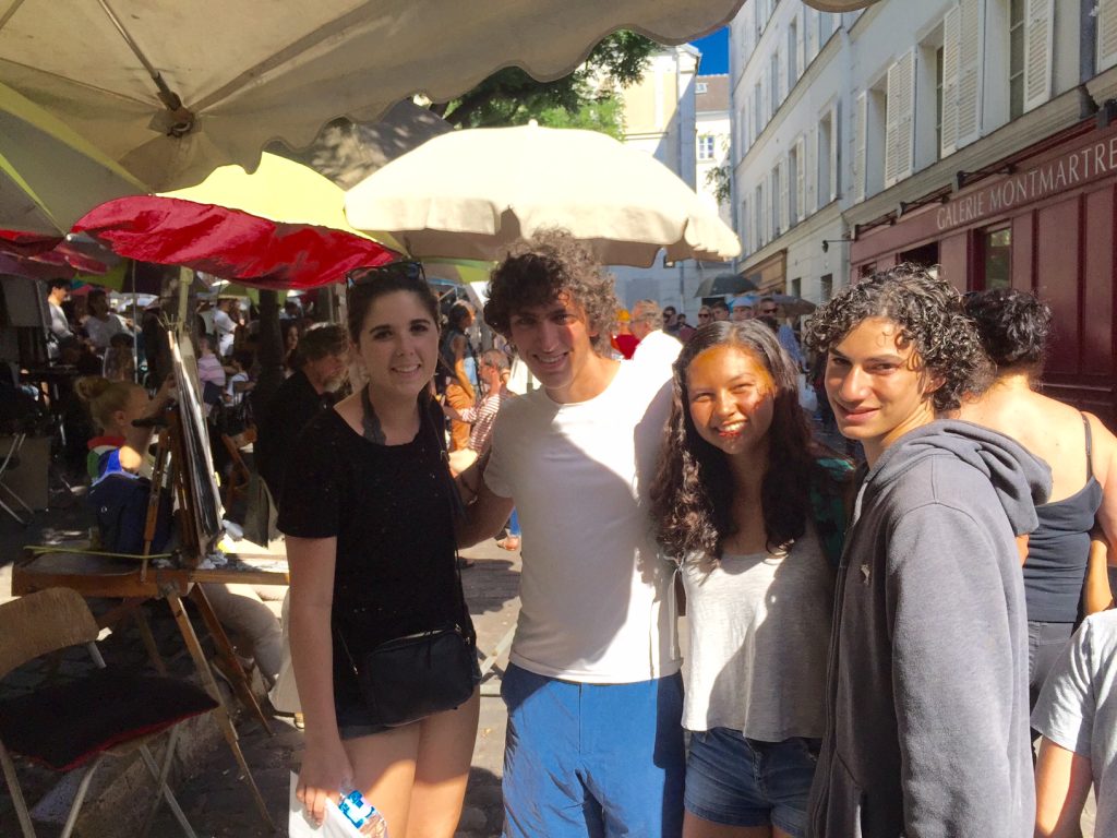 Taylor, Kaes, Kelsey, and Jacob (re)pose among the umbrellas and the art.